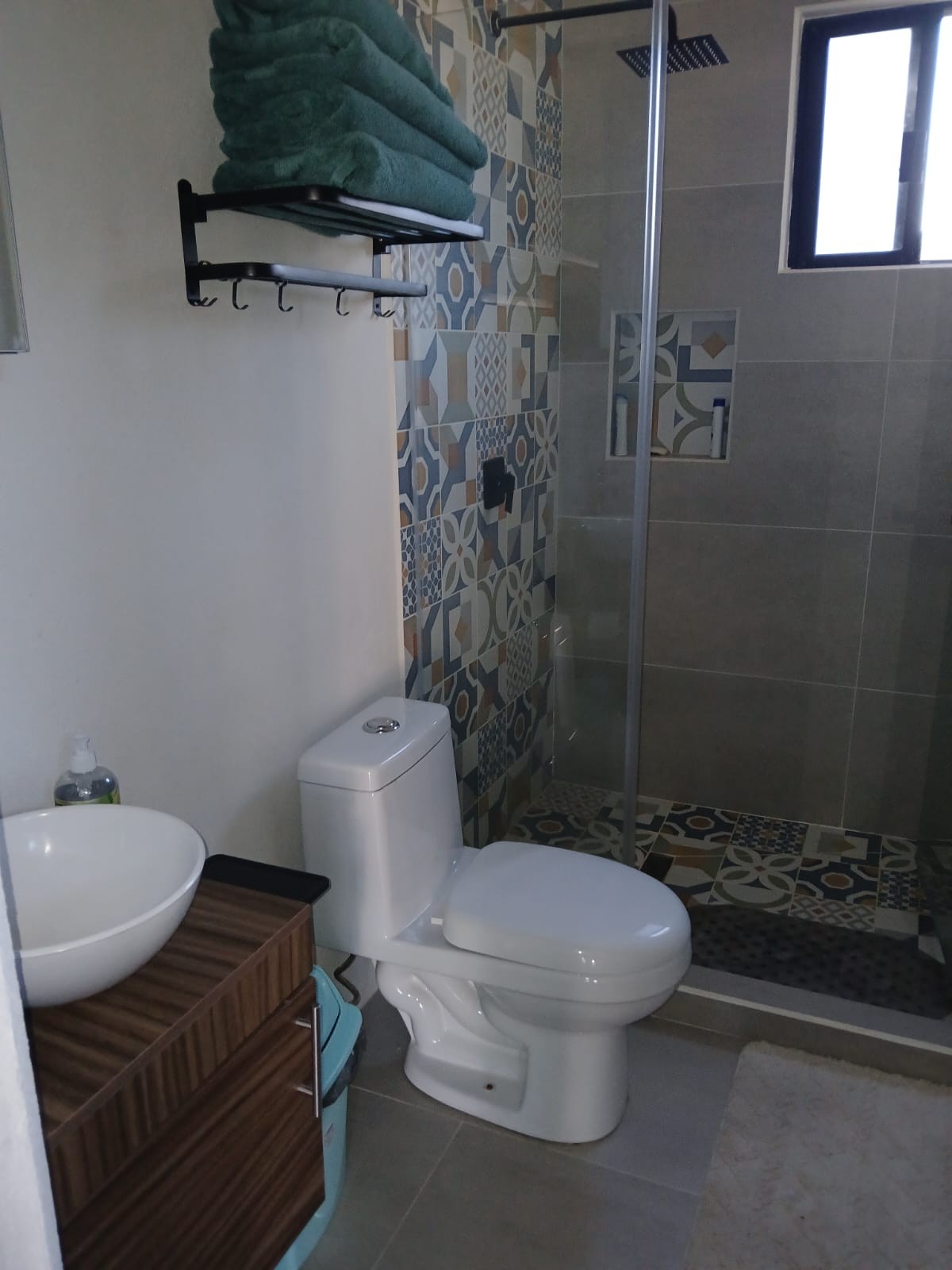 Baño completo con regadera, mosaico de colores y toallas