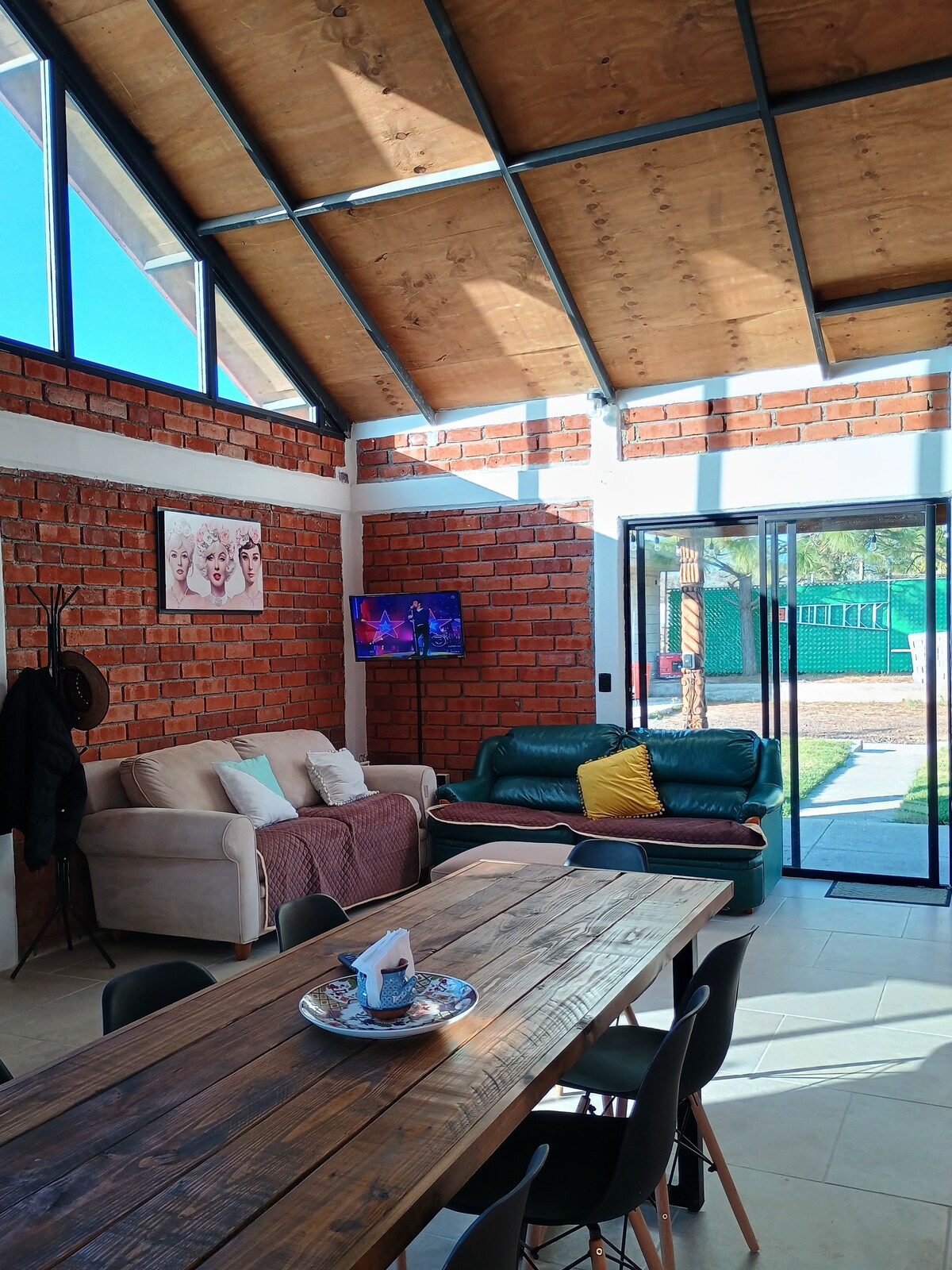 Interior del quiosco con mesa larga para reuniones, sofás y TV