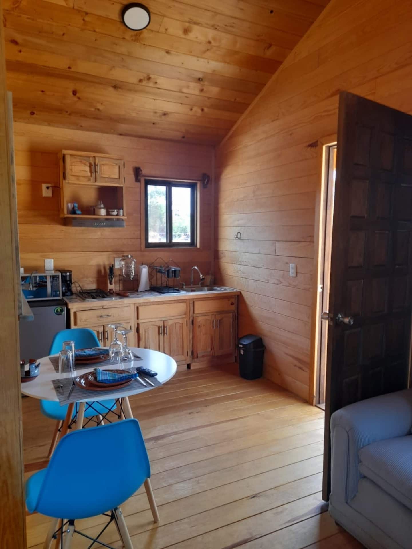 Interior de cabaña con cocineta equipada y comedor para dos