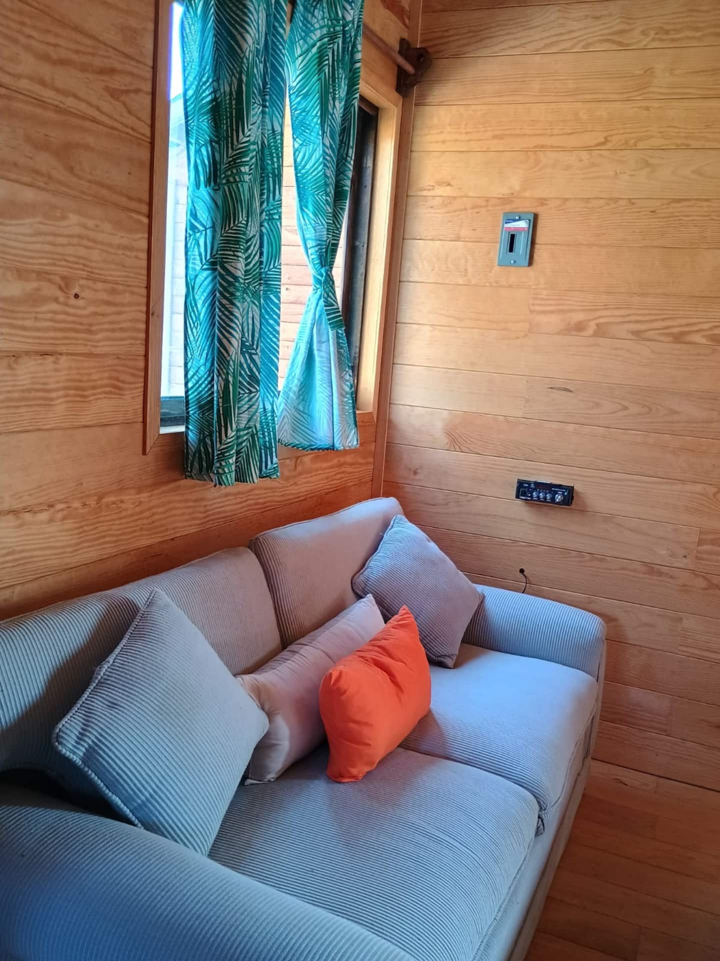 Sala de estar de la cabaña con sofá y cortinas tropicales