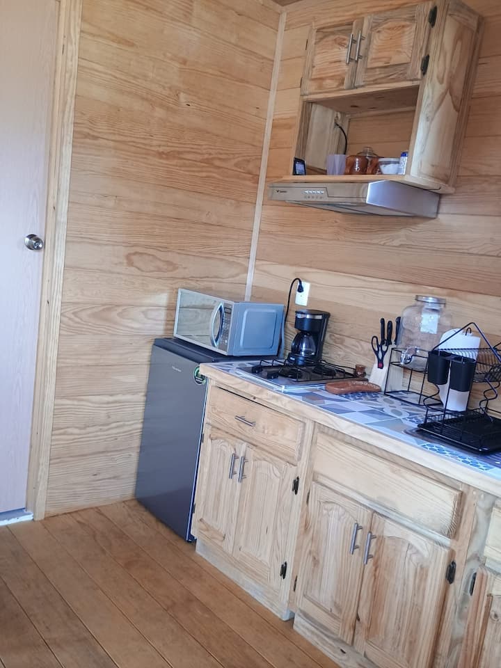 Detalle de la cocineta: cafetera, estufa, refrigerador y microondas